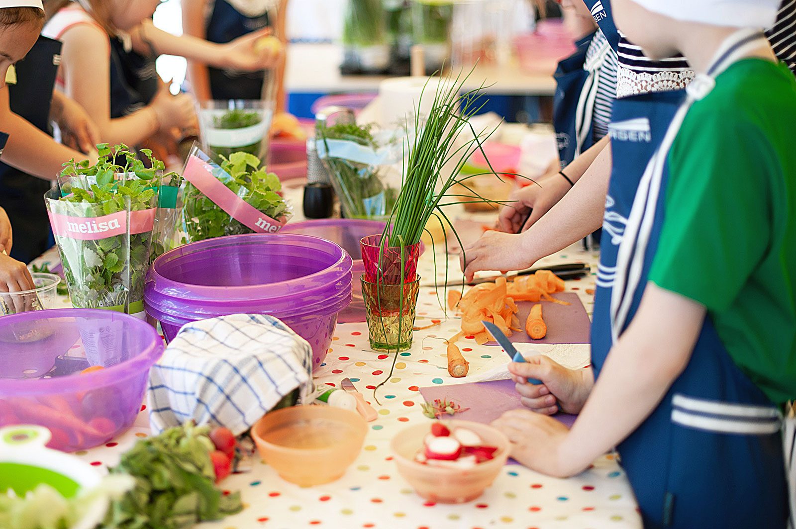 Crianças a preparar alimentos, sobre uma mesa, para posterior confecção.
